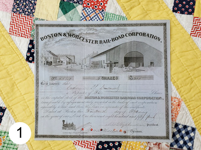 1854 stock certificate of the Boston & Worcester Rail-Road photographed against a quilt